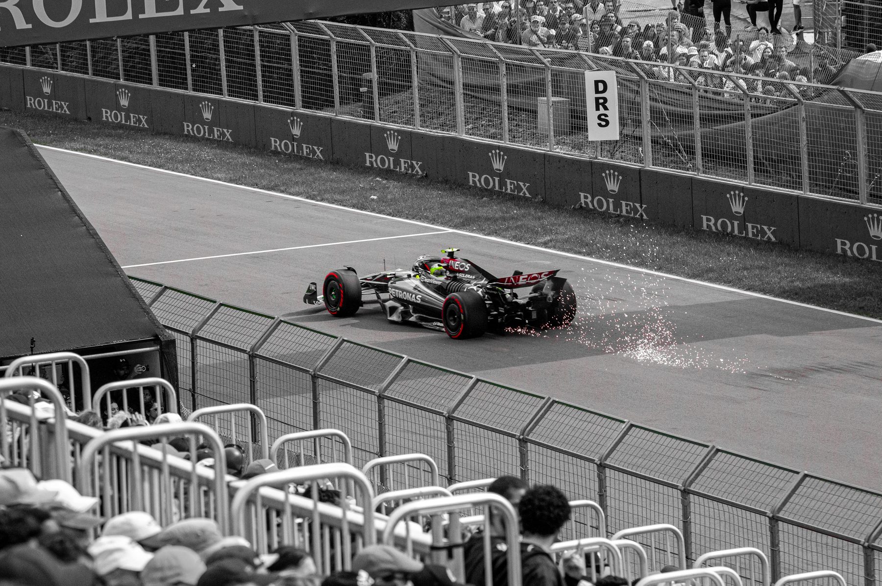 A Formula 1 car throwing sparks on the track, black-and-white photo with red accents